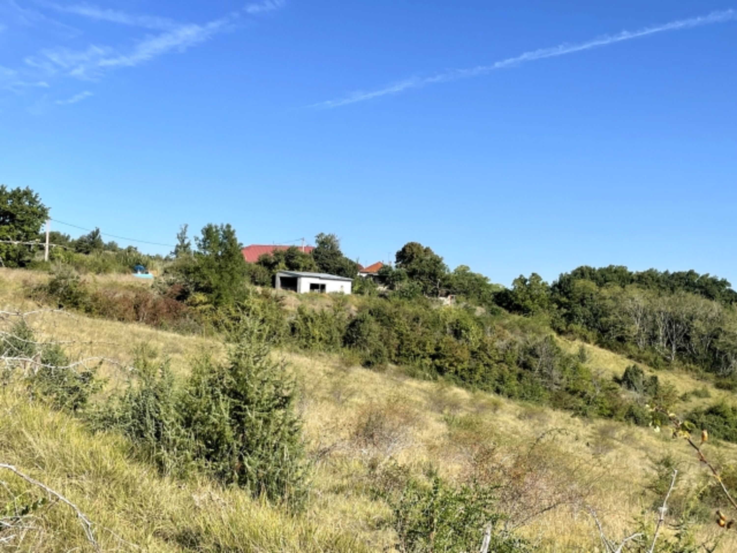 Blick über eigenes Land über den Stall zum Haus