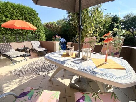 Sonnenterrasse mit Liegen und Abgang zum eingezäunten Gartenteil