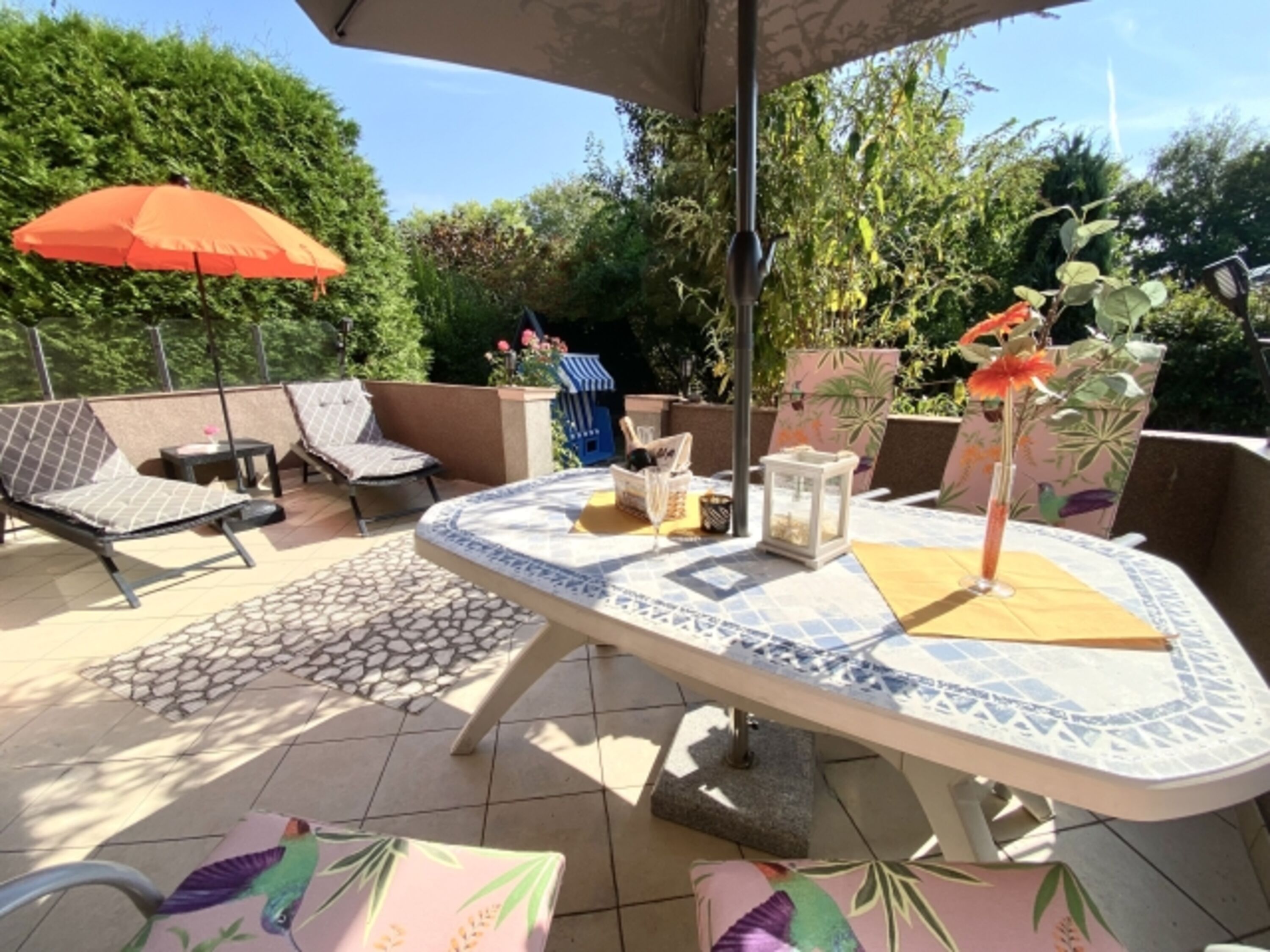 Sonnenterrasse mit Liegen und Abgang zum eingezäunten Gartenteil