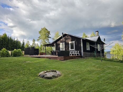 Die hinter dem Haus befindliche Terrasse mit Blick auf den Wald . Im Vordergrund die Feuerstelle für den Grill