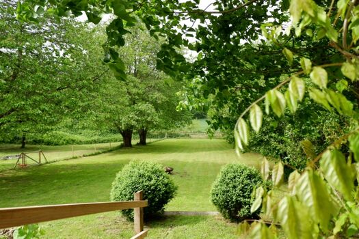 Blick in den großen, eingezäunten Garten mit Feuerschale