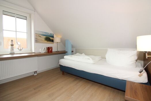 Zimmer im Dachgeschoß mit einem Fernseher und zwei getrennten Betten