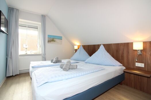 Schlafzimmer mit Doppelbett, Fernseher und großem Schrank