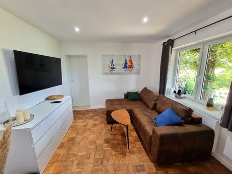 Wohnzimmer mit gemütlicher Couch und SAT TV