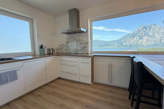 Moderne Küche in weiß mit Panorama Seeblick und Esstisch.