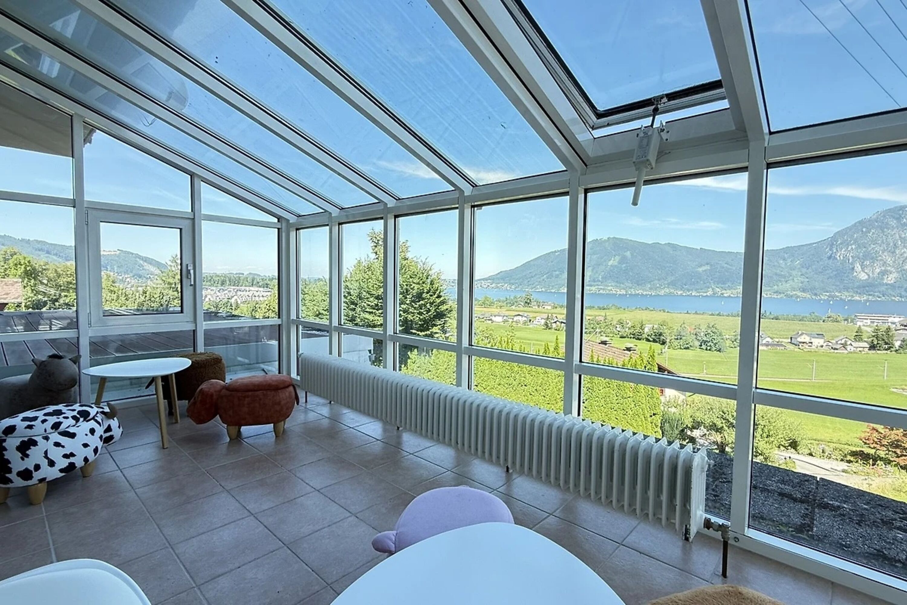 An Wohnzimmer angrenzender Wintergarten mit Panorama Seeblick und Bergblick.