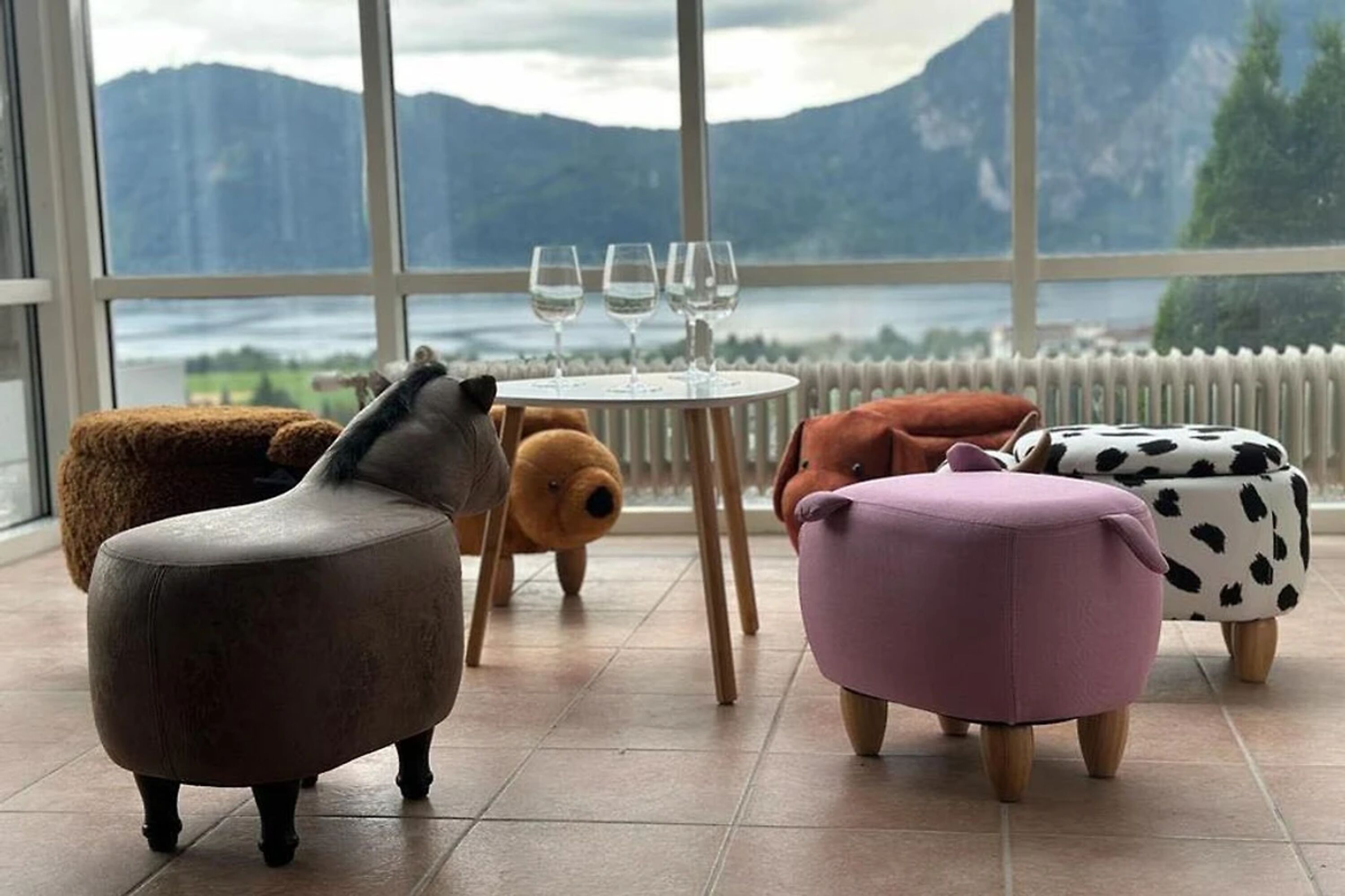 Ans Wohnzimmer angrenzender Wintergarten mit Panorama Seeblick und Tier Hockern.