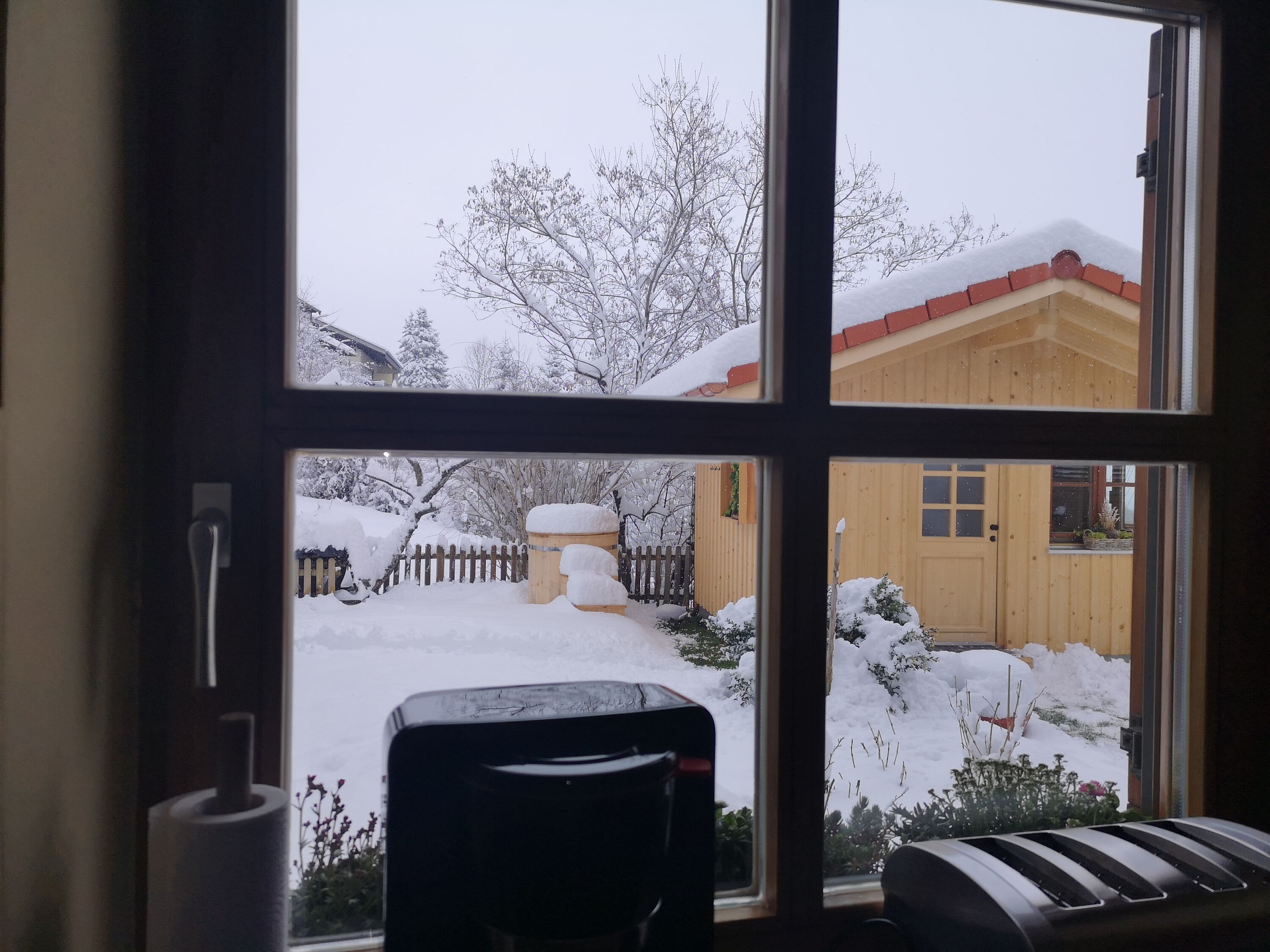 Küchenfenster mit Blick auf die Gartensauna mit Eisfasstauchbecken