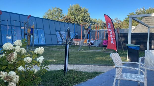 Spielbereich im Park und Hallenbad im Hintergrund