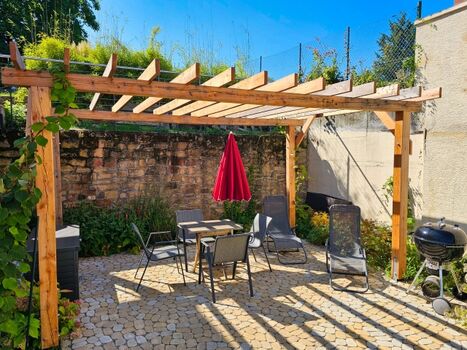 Terrasse mit Grill, Sitzmöglichkeit und Liegestühlen im Hof