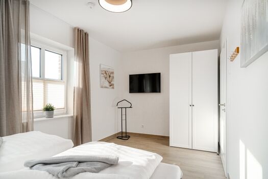 Schlafzimmer mit ausreichend Stauraum und TV