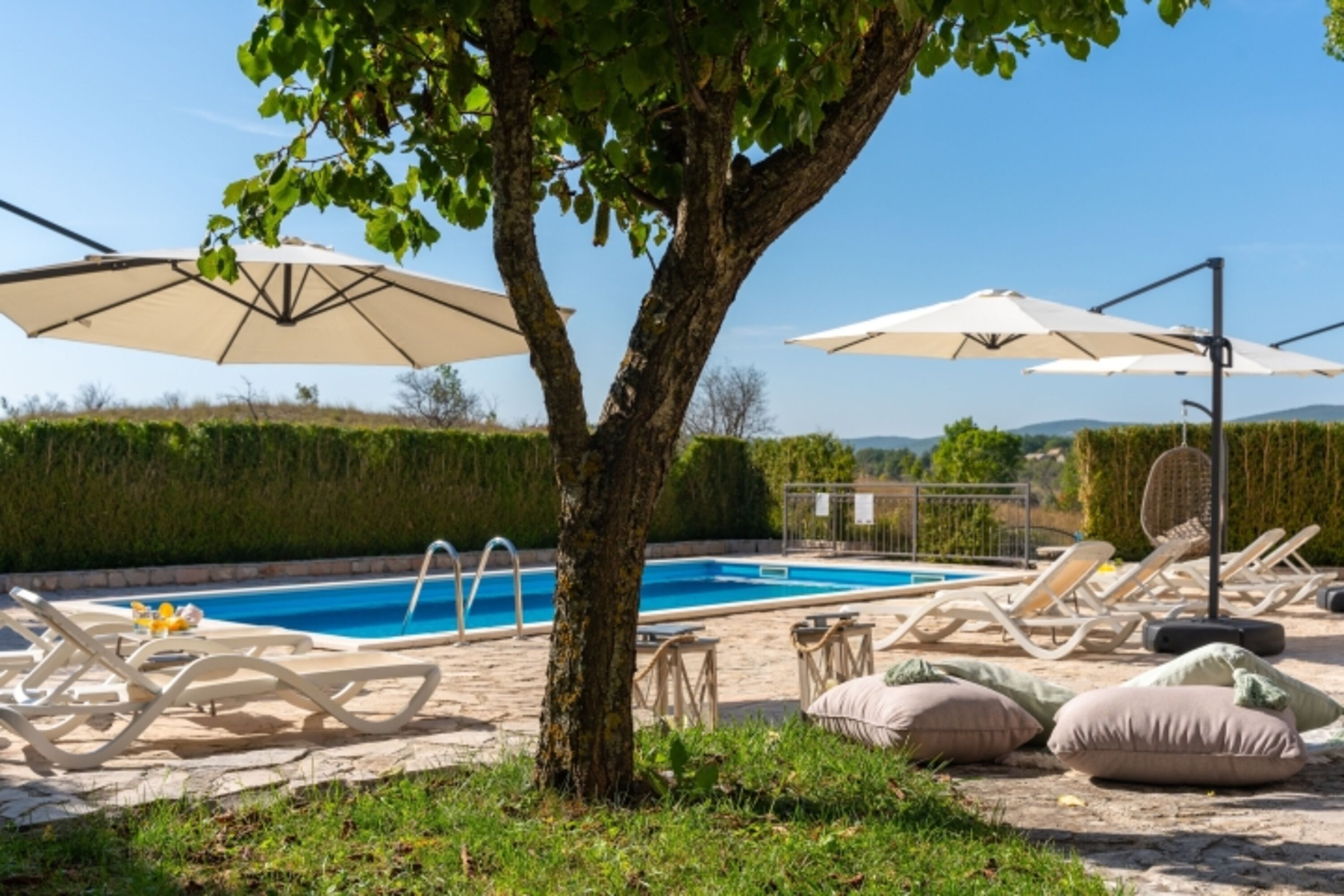 Ruhiger Außenbereich mit Swimmingpool, umgeben von Liegestühlen und Sonnenschirmen, die Schatten spenden