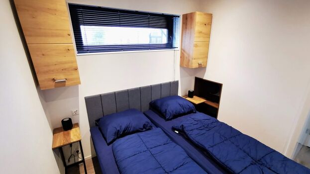 Zweites Schlafzimmer mit Hängeschränken und Ablagefach.