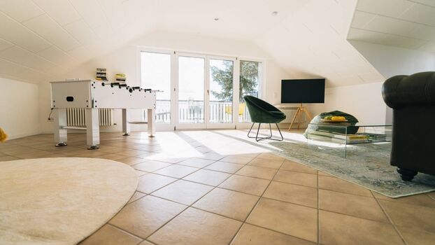 Das riesige Wohnzimmer: Vintage Chesterfield-Couch, Sitzsack, Lesesessel und Kicker mit gelben Details.