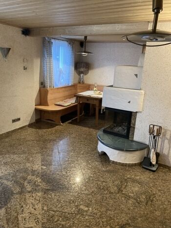 Wohnzimmer mit Kaminofen, Granitfußboden und Couch zum Bett umwandelbar