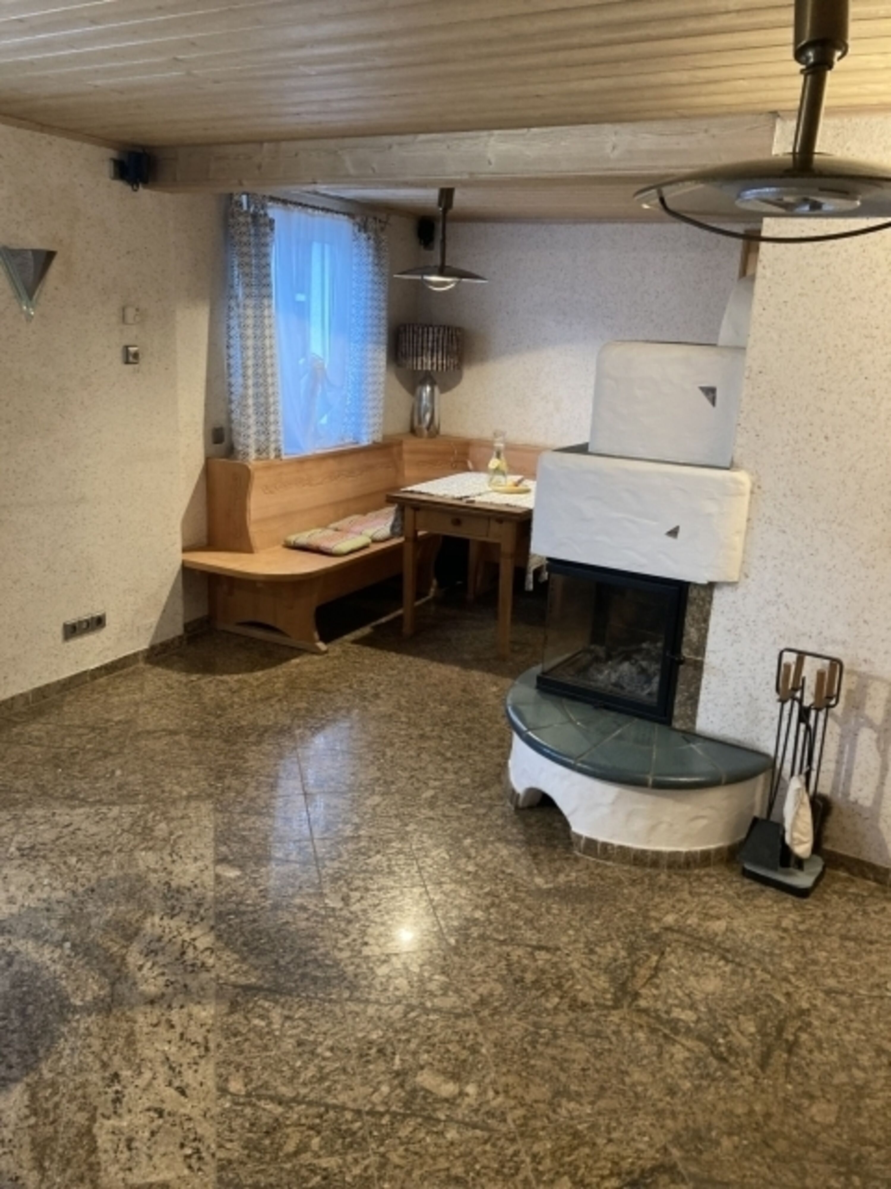 Wohnzimmer mit Kaminofen, Granitfußboden und Couch zum Bett umwandelbar