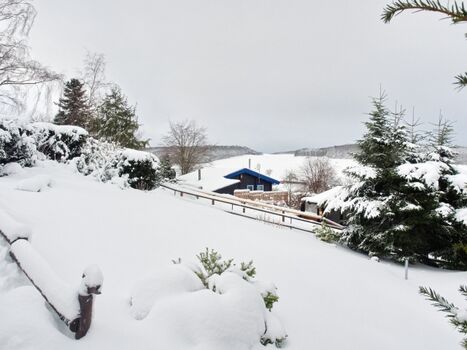 Blick über das tief verschneite Feriendorf auf das Ferienhäuschen zum WOHLFÜHLEN