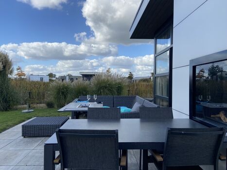 Große Terrasse mit gemütlicher Sitzlounge und Esstisch am Kamin