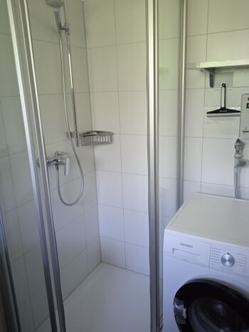 Dusche und Münzwaschmaschine im Bad