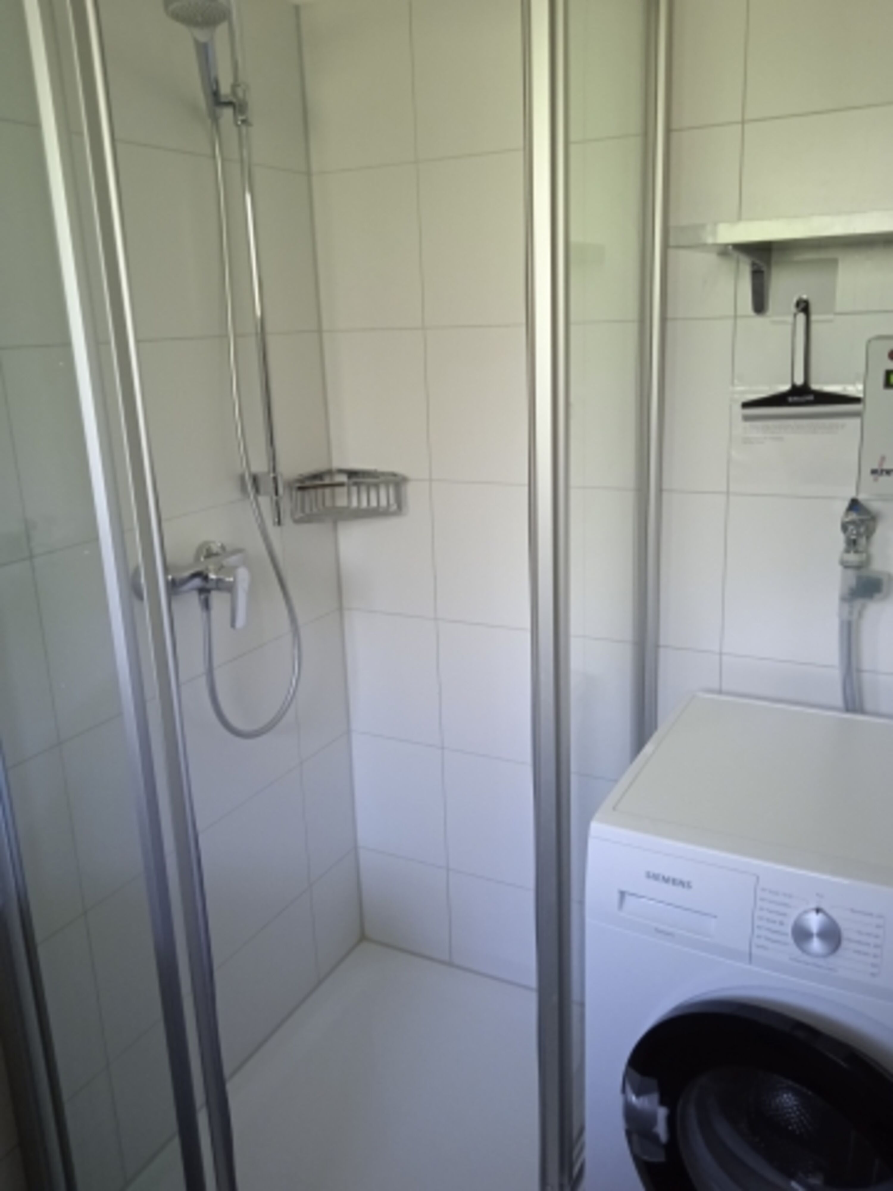 Dusche und Münzwaschmaschine im Bad