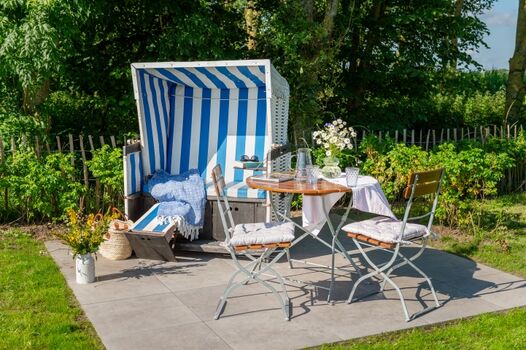 Terrasse im eingezäunten Garten mit Strandkorb