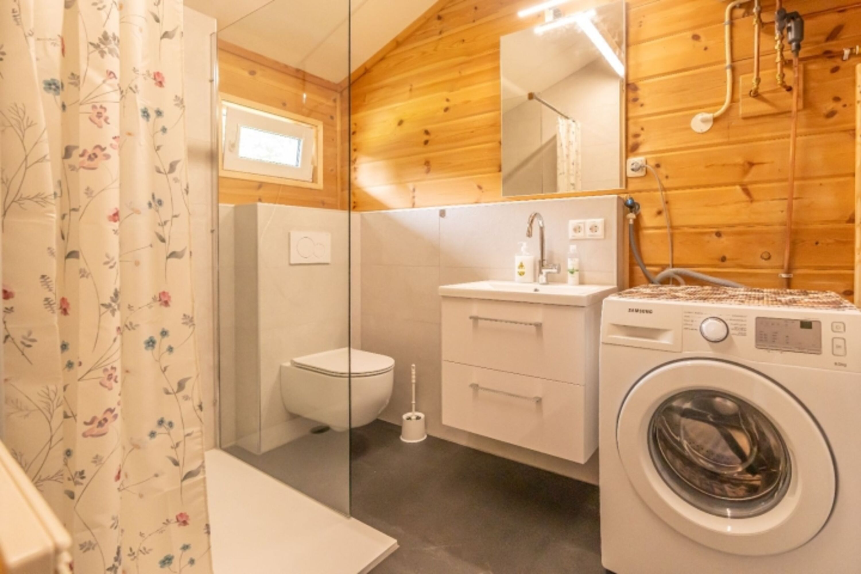 Das Badezimmer mit Dusche, Waschbecken, WC und Waschmaschine