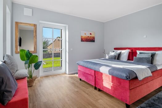 Schlafzimmer mit Boxspringbett und Zugang zur Terrasse