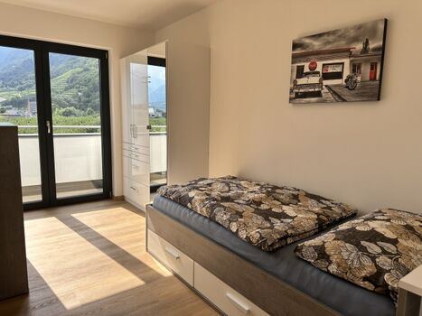 Zimmer mit Einzelbett und Zugang zum Balkon