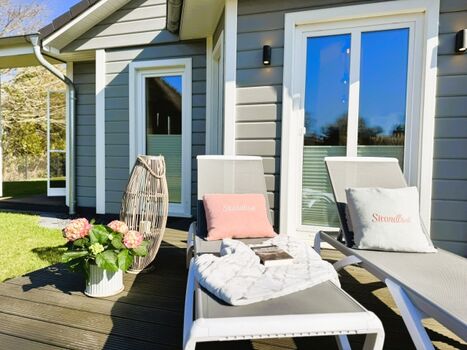 Sonnige Terrasse mit Sonnenliegen im eingezäunten Garten