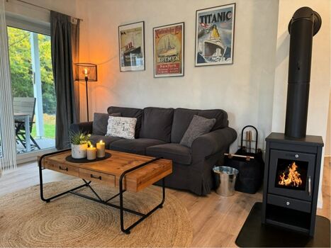 Gemütlicher Wohnbereich mit Couch, Kaminofen und Terrassenzugang