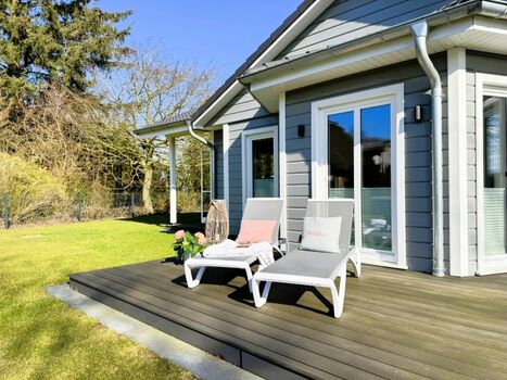 Sonnige Terrasse mit Sonnenliegen im eingezäunten Garten