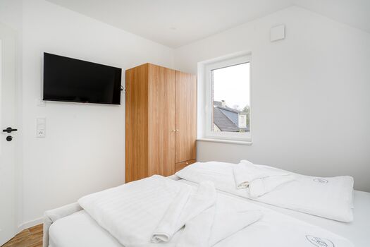 Schlafzimmer mit Doppelbett und TV