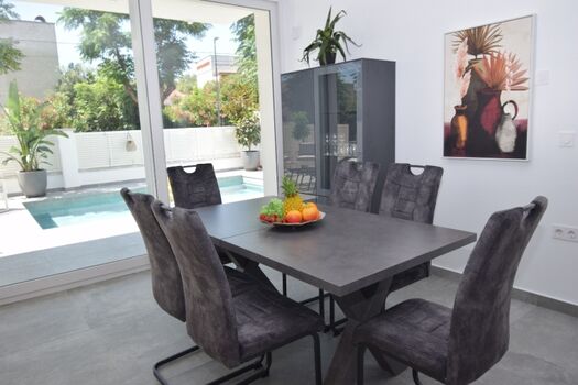 Essbereich mit Tisch und Stühlen – alles mit Blick zum Pool