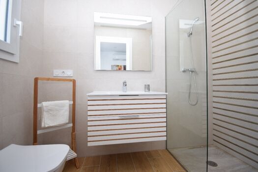 Bad en Suite mit ebenerdiger Dusche, Waschbecken und WC