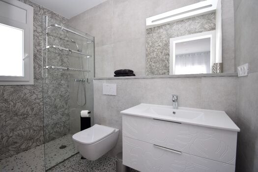 Bad en Suite mit ebenerdiger Dusche, Waschbecken und WC