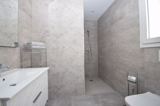 Bad en Suite mit ebenerdiger Dusche, Waschbecken und WC