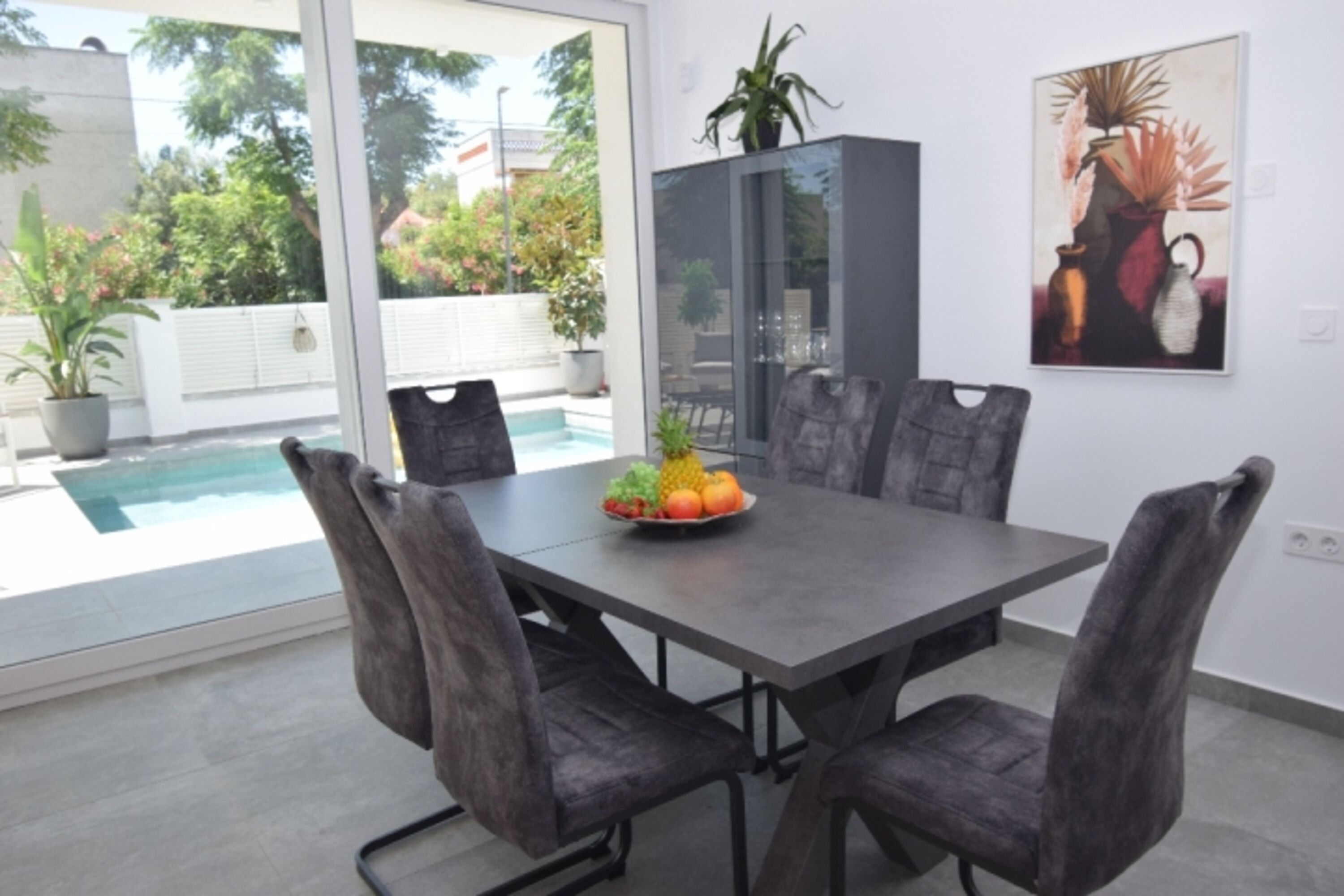 Essbereich mit Tisch und Stühlen – alles mit Blick zum Pool