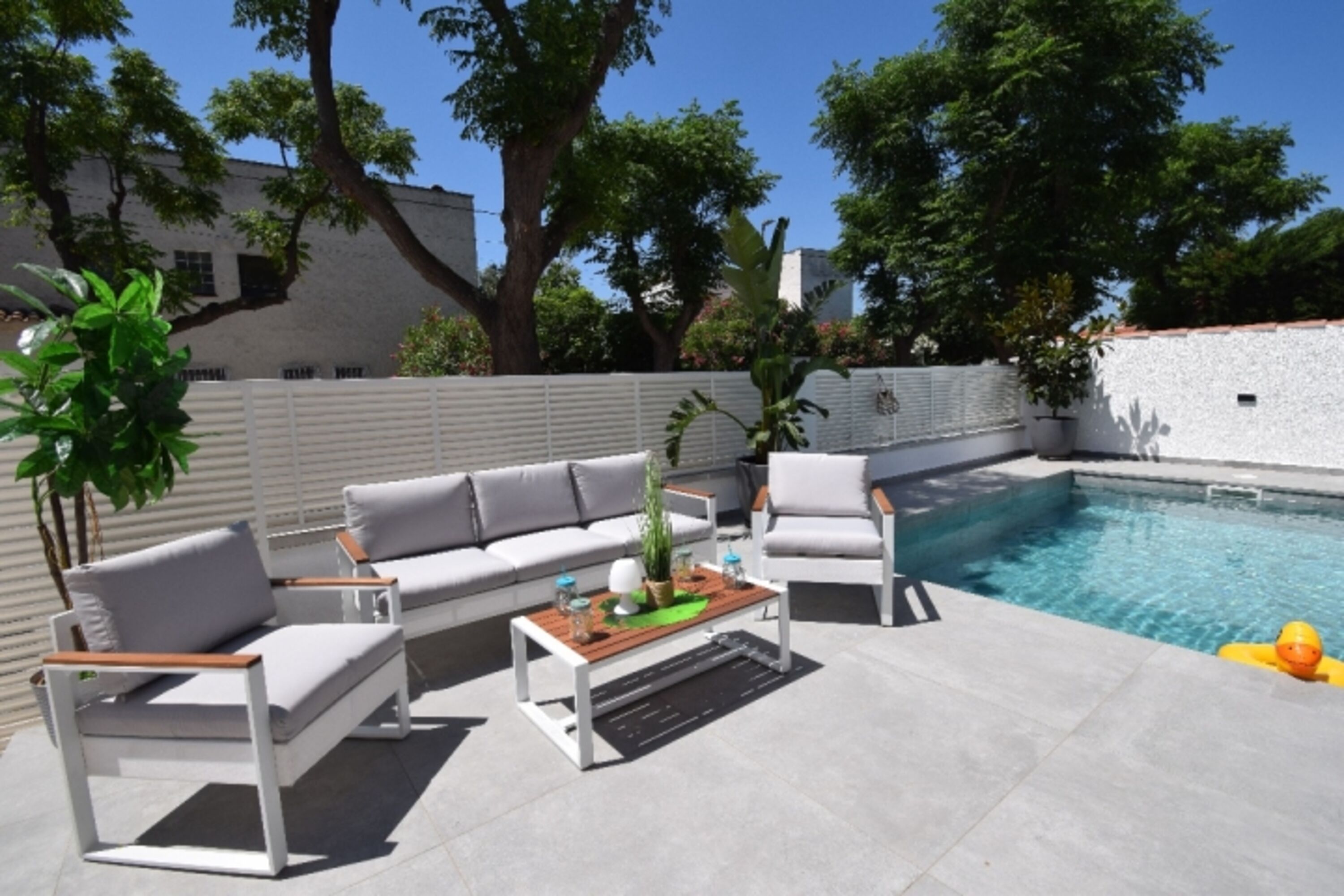 Teilüberdachte Terrasse mit: Markise, Esstisch Stühlen, Holzkohlegrill, Loungebereich, Sonnenliegen.