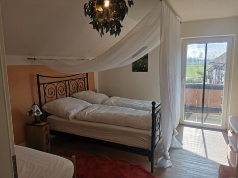 Schlafzimmer 2 mit Himmelbett, einem Einzelbett und Zugang zum Balkon