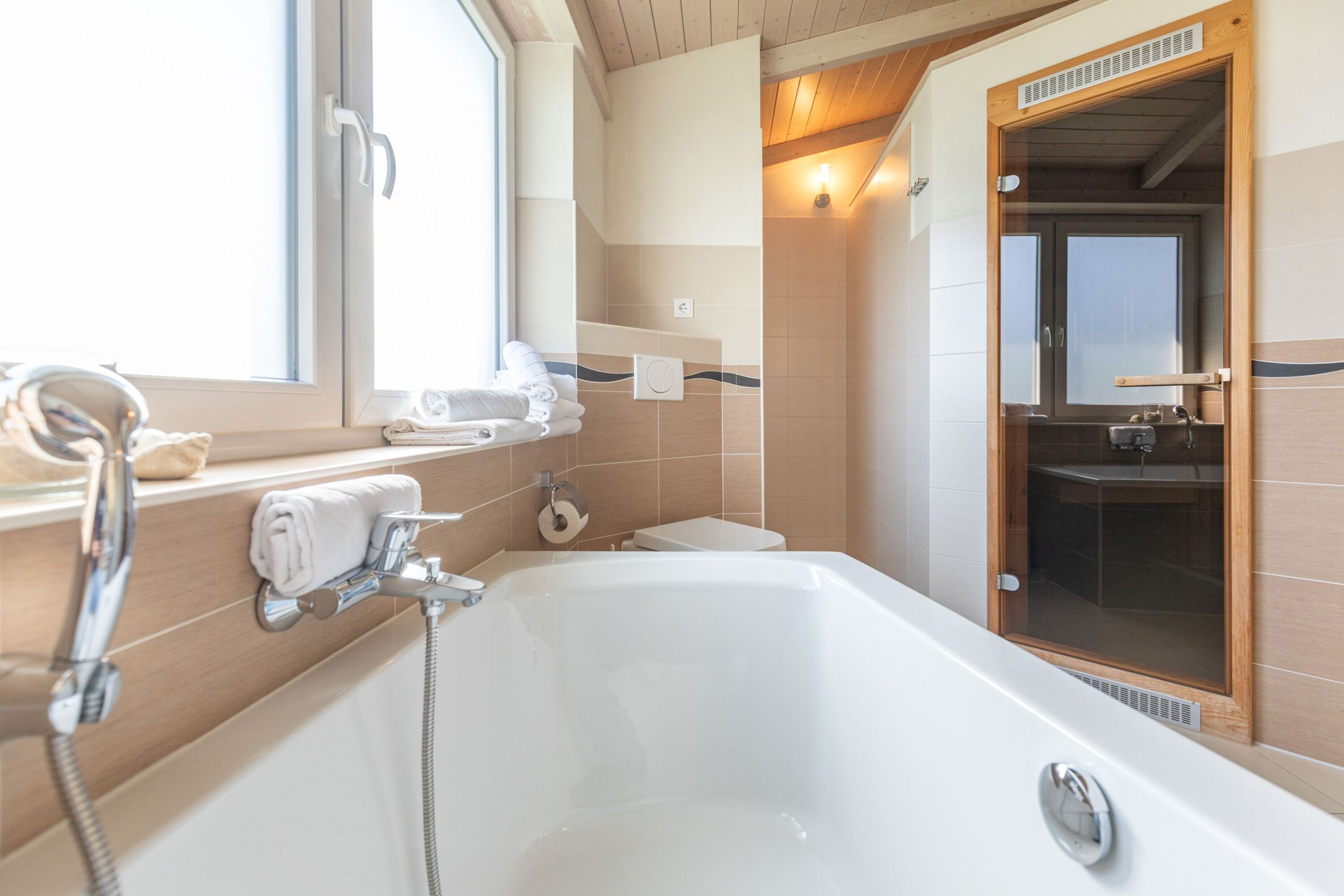 Ferienhaus Hallig Hooge – Helles Badezimmer mit Badewanne und angrenzender Sauna
