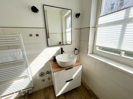 Helles Badezimmer mit stilvollem Waschtisch und viel Tageslicht