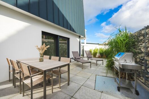 Terrasse mit Gartenmöbeln, Sonnenschirm und Grill