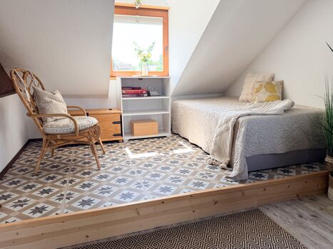 Boxspringbett 1,00 x 2,00m im Obergeschoss. Das Bett steht auf einem Podest unter einer Dachschräge.