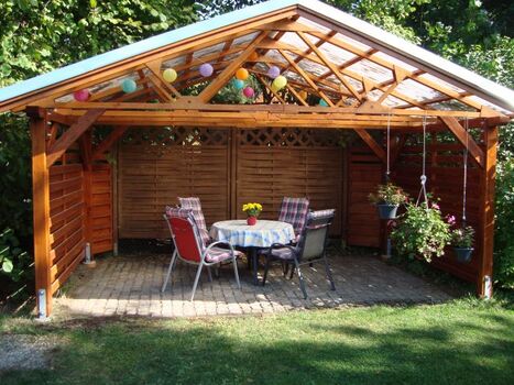 Überdachter Grillplatz mit Gartenmöbeln und Grill