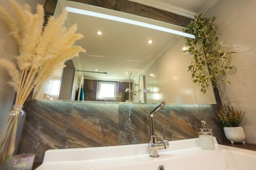 Unser beheizter Spiegel bleibt auch nach einer heißen Dusche hell. Die natürlichen Akzente wie Pampasgras und Hängepflanzen schaffen eine frische und friedliche Atmosphäre.