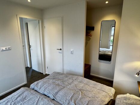 Offen gestalteter Kleiderschrank und Zugang zum Bad