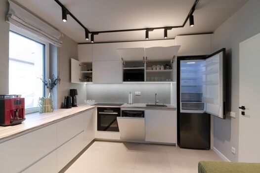 Moderne L-förmige Küche mit weiß matten Fronten und Einbaugeräten: Siemens Induktionskochfeld, Bosch Pyrolyse-Backofen, LG Kühl-Gefrierkombi, Bosch Spülmaschine. Unterbau-LEDs und große Arbeitsfläche am Fenster sorgen für perfekte Lichtverhältnisse.