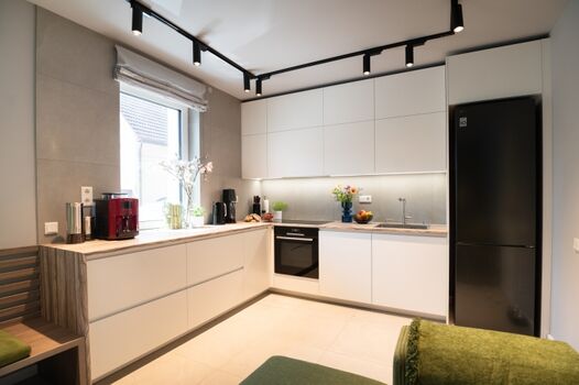 Moderne L-förmige Küche mit weiß matten Fronten und Einbaugeräten: Siemens Induktionskochfeld, Bosch Pyrolyse-Backofen, LG Kühl-Gefrierkombi, Bosch Spülmaschine. Unterbau-LEDs und große Arbeitsfläche am Fenster sorgen für perfekte Lichtverhältnisse.