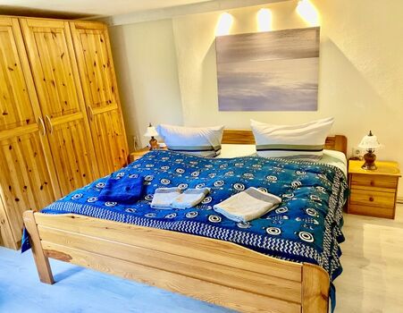 Im Schlafzimmer bietet der große Kleiderschrank viel Stauraum. Das Bett ist aus Holz und knarrt ein bisschen.