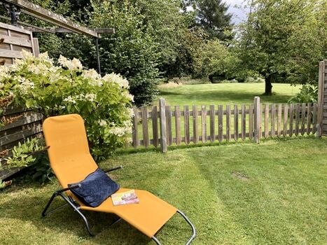 Eingezäunter Garten mit Rasenfläche und Terrasse hinter dem Haus